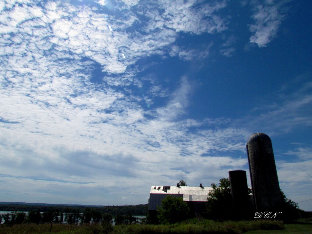 Picture of an old barn and silo set against a sparsely clouded blue sky.